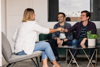 A couple shaking hands with a real estate agent after making as deal